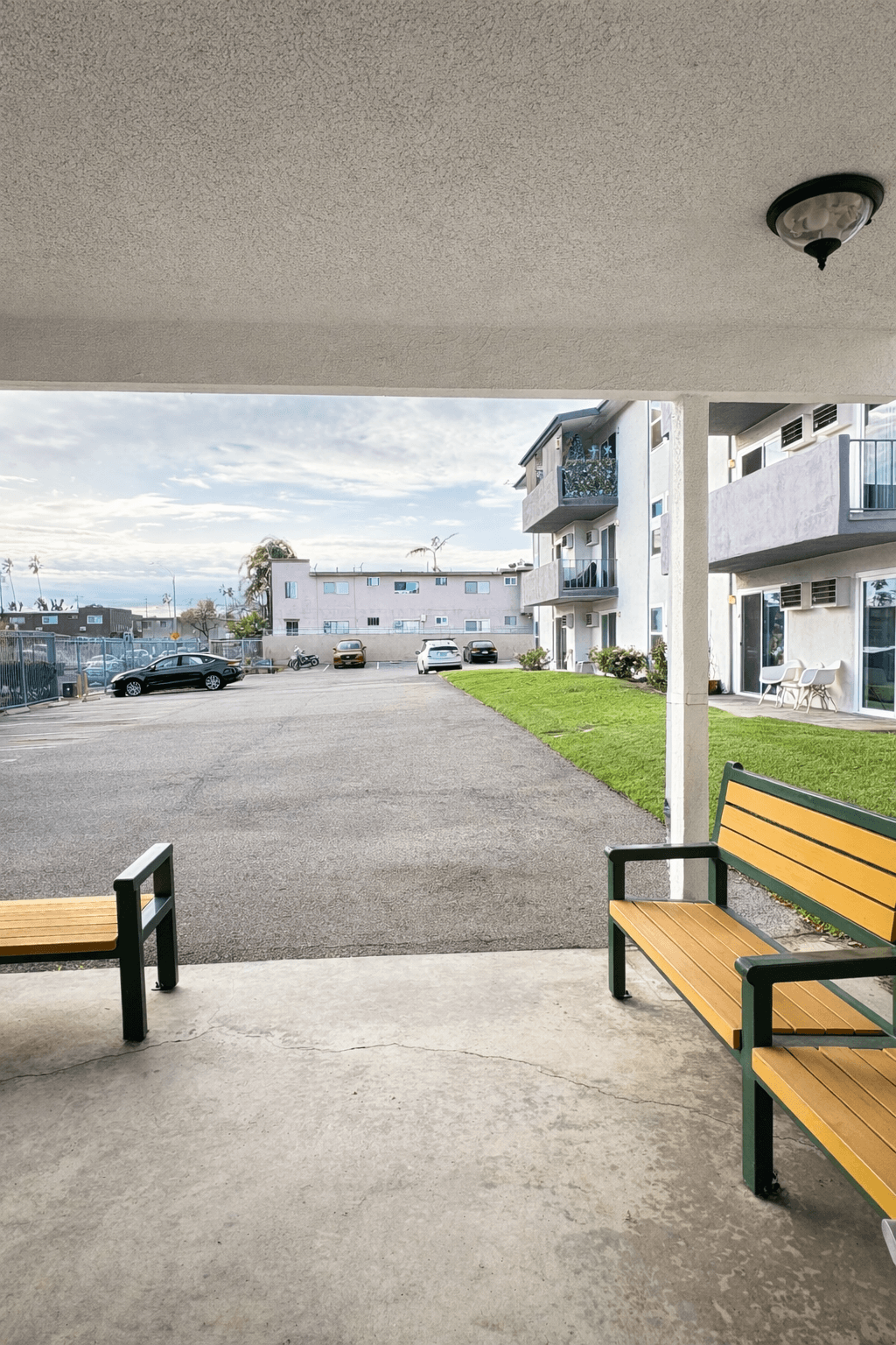 A bench with a wooden seat and green frame is on a concrete surface.